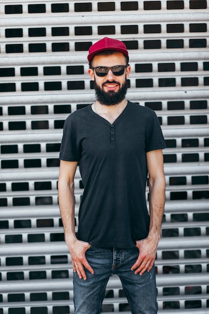 Un joven elegante con barba en una camiseta negra y gafas