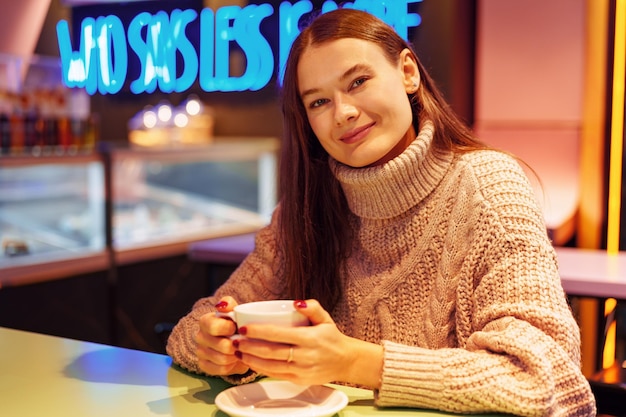 Una joven elegante bebiendo café en la cafetería.
