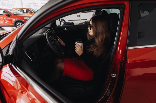 Una joven elegante busca un auto nuevo en una tienda de autos