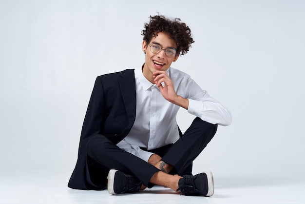 Joven elegante con el cabello rizado y en un traje clásico en un fondo claro en el interior en pleno crecimiento foto de alta calidad