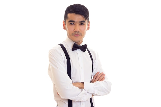 Joven elegante con camisa blanca con corbatín negro y tirantes negros en el estudio