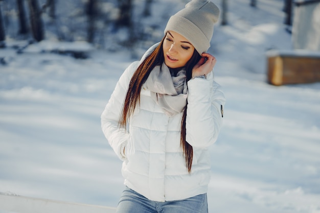 joven y elegante chica snadning en un parque de invierno cubierto de nieve