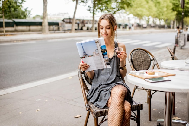 Joven elegante diario de lectura sentado al aire libre en el café en París