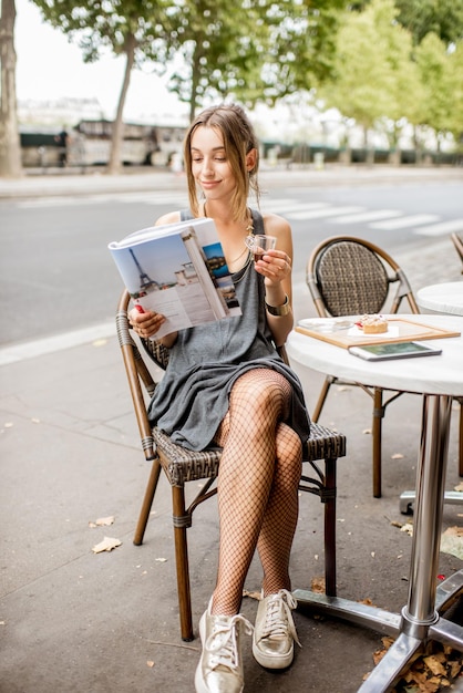 Joven elegante diario de lectura sentado al aire libre en el café en París