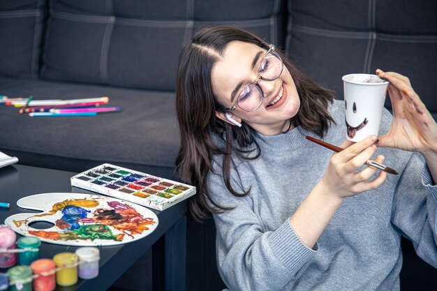 Una joven elegante dibuja con pinturas en el interior de la casa