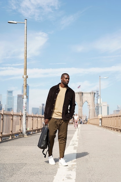 Foto joven elegante explorando un puente de la ciudad por sí mismo