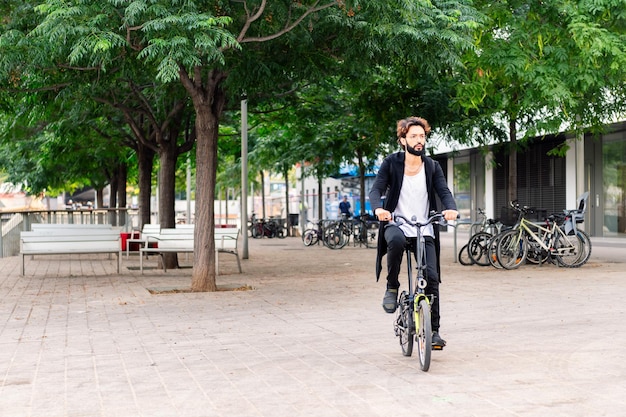 Joven elegante montando su bicicleta por la ciudad