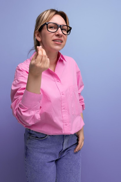 La joven y elegante secretaria caucásica rubia con gafas está vestida con una blusa rosa