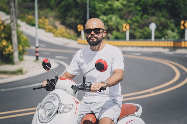 Joven elegante con su motocicleta en la carretera