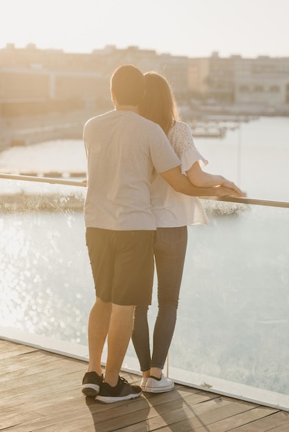 Un joven elegante se toma de la mano con su novia morena en el puerto