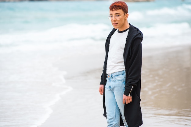 Joven elegante weared está posando en una playa