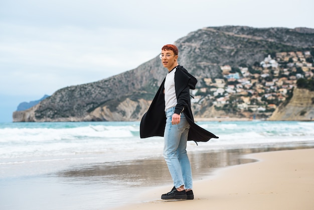 Joven elegante weared está posando en una playa