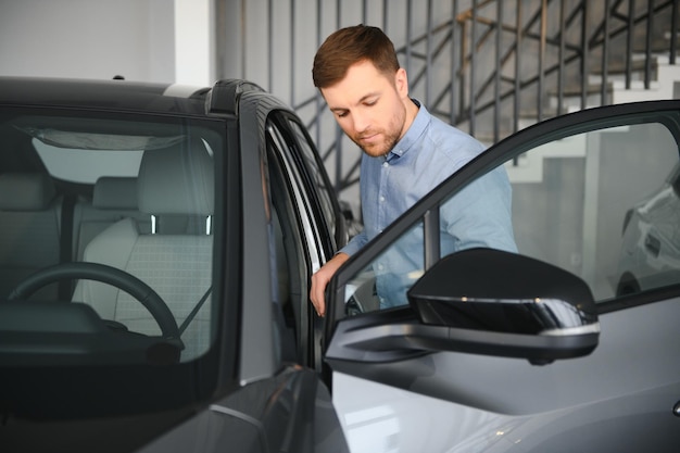 Un joven elige un coche nuevo en un concesionario de automóviles