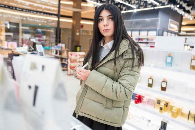 Una joven elige perfume en una tienda.