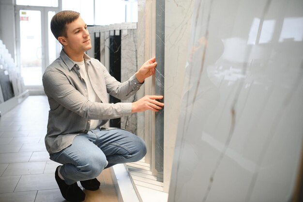 Un joven eligiendo azulejos en el mercado de la construcción