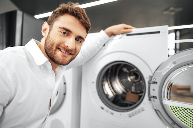 Joven eligiendo nueva lavadora en la tienda de electrodomésticos