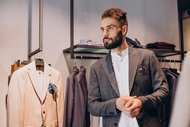 Joven eligiendo paños en la tienda de ropa masculina