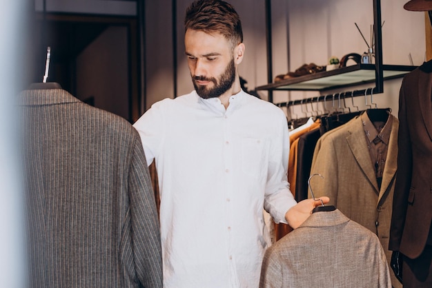 Joven eligiendo paños en la tienda de ropa masculina