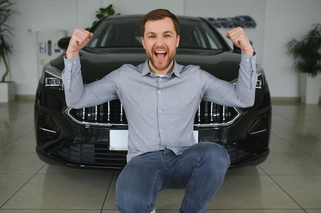 Foto el joven está eligiendo un vehículo nuevo en un concesionario de automóviles