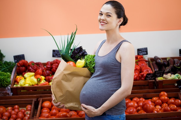 Joven embarazada de compras en una tienda de verduras