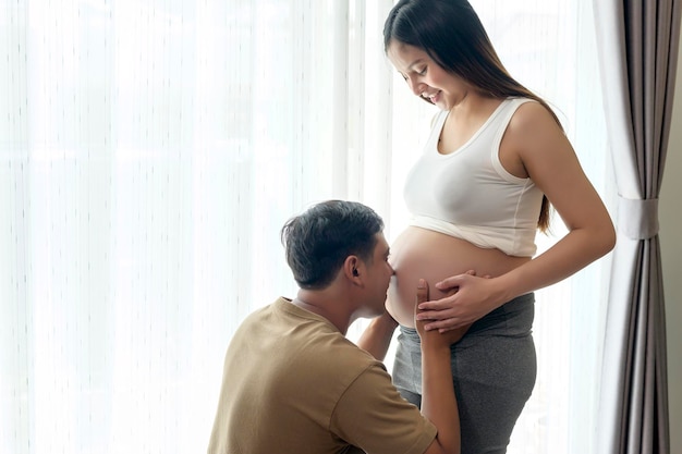 Joven embarazada con esposo abrazando y esperando un bebé en casa