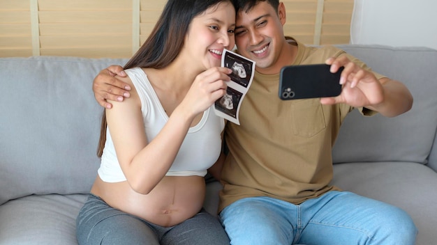 Joven embarazada con esposo abrazándose y videollamada con familiares y amigos por teléfono inteligente