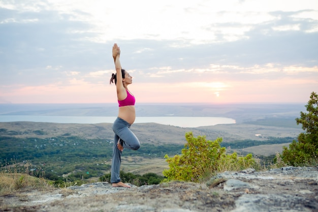 Joven embarazada hace yoga al aire libre