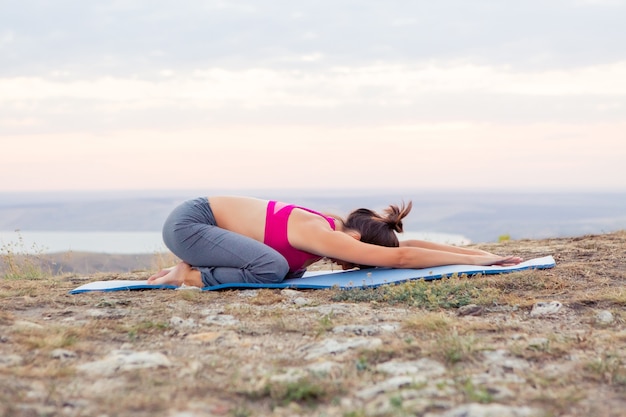 Joven embarazada hace yoga al aire libre