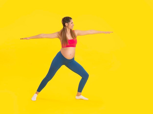 Foto joven embarazada haciendo ejercicio de pilates con la mano y la pierna estiradas