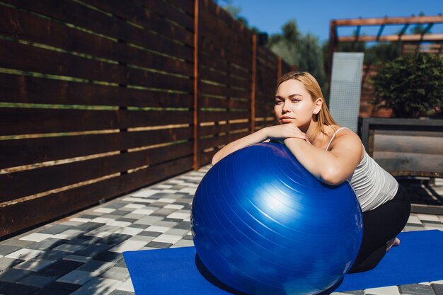 Joven embarazada haciendo ejercicio de relajación con una pelota de fitness al aire libre