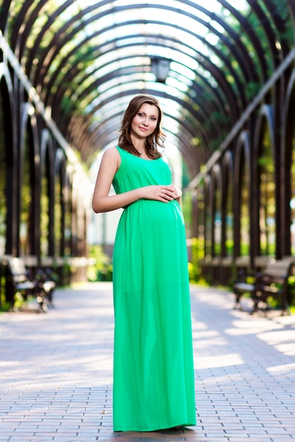 Joven embarazada posando en un vestido verde