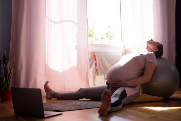 Joven embarazada practica yoga en casa