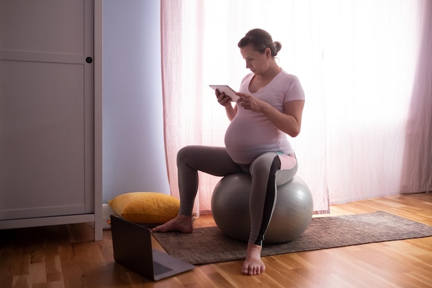 Joven embarazada practica yoga en casa