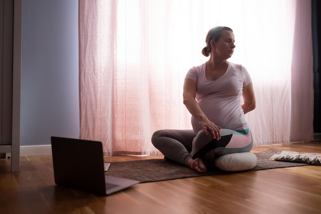 Joven embarazada practica yoga en casa