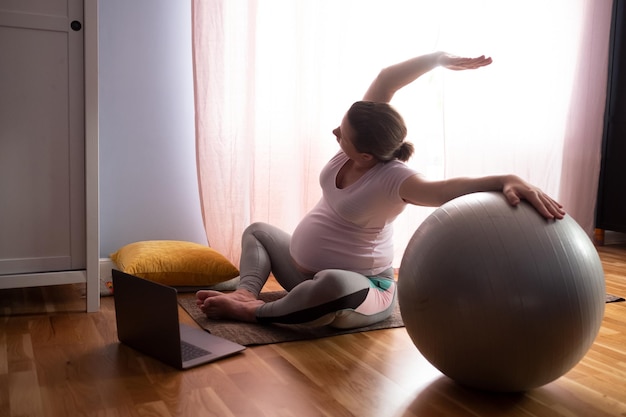 Joven embarazada practica yoga en casa