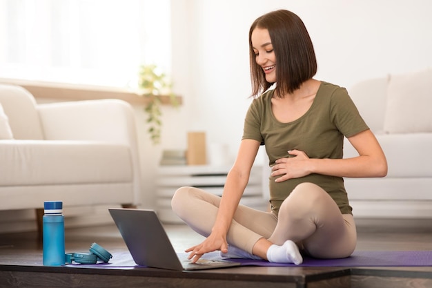 Foto una joven embarazada practica yoga prenatal usando la computadora en casa