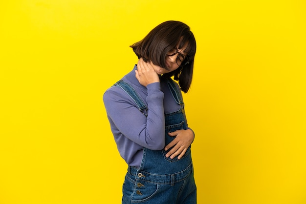 Joven embarazada sobre fondo amarillo aislado con dolor de cuello