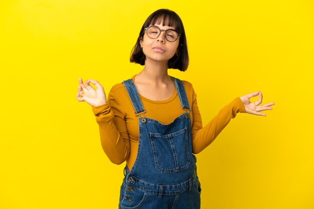 Foto joven embarazada sobre fondo amarillo aislado en pose zen