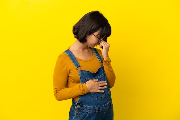 Foto joven embarazada sobre fondo amarillo aislado que tiene dudas