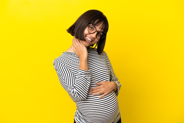 Joven embarazada sobre fondo amarillo aislado riendo