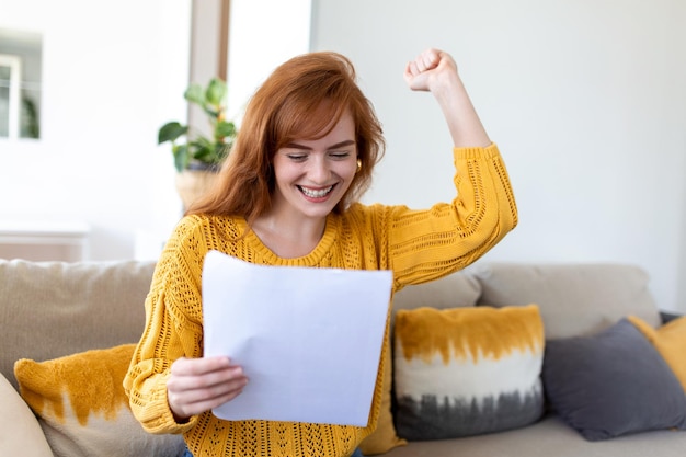 Una joven emocionada sostiene una carta en papel y se siente eufórica al recibir un ascenso laboral o un reembolso de impuestos del banco. Una mujer feliz leyendo un documento de papeleo sonriendo de buenas noticias agradables obteniendo una beca para estudiantes.