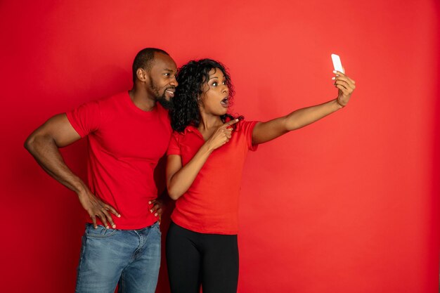 Joven emocional afroamericano y mujer en rojo