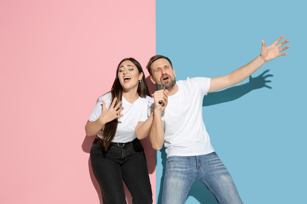 Joven emocional y mujer en pared rosa y azul