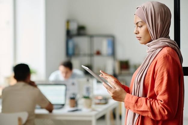 Joven empleada con hijab usando una tableta