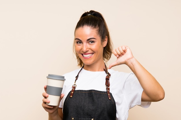 Joven empleada sosteniendo un café para llevar orgulloso y satisfecho