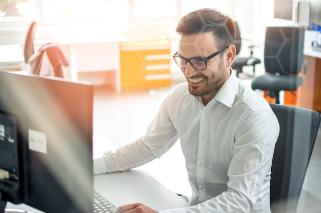 Joven empleado con gafas usando computadora en la oficina