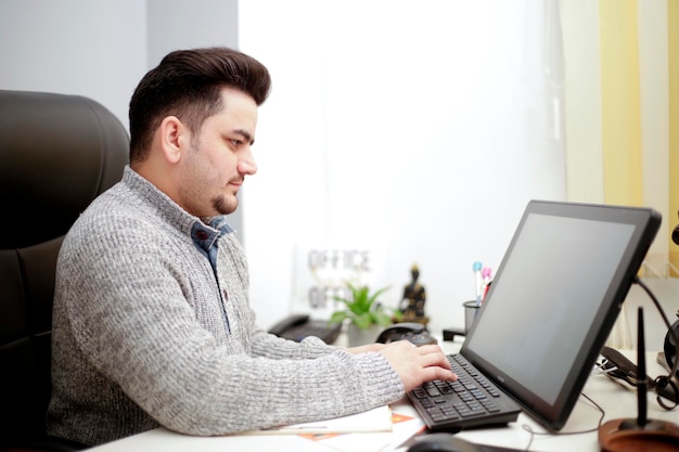 Un joven empleado que trabaja en la computadora.