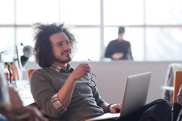 Joven emprendedor independiente que trabaja con una computadora portátil y en un espacio de coworking