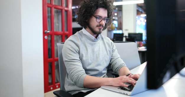 Joven emprendedor independiente que trabaja con una computadora portátil en el espacio de coworking