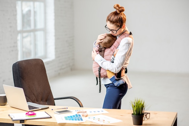 Joven empresaria abrazando a su hijo en el lugar de trabajo en la oficina